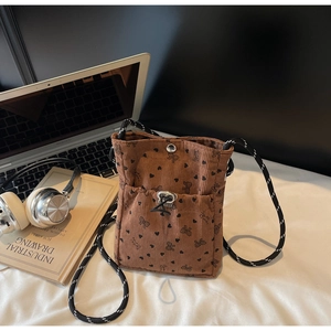 Brown corduroy crossbody phone bag with heart and bow patterns in a cozy desk setup