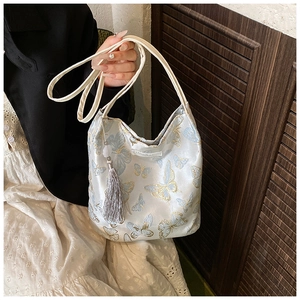 Gros plan du sac en toile avec broderie papillon bleu et détail de pompon argenté