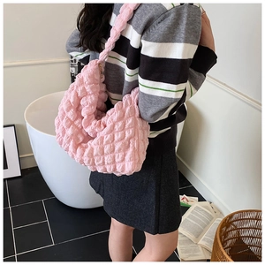Pink bubble pleated hobo bag shown on shoulder in a minimalist indoor setting