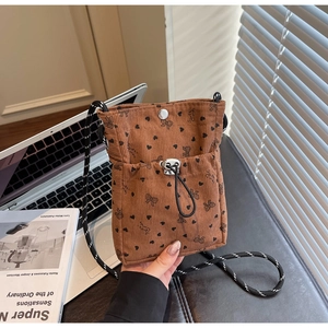 Close-up of brown corduroy crossbody bag with heart bow patterns on an office desk