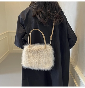 Close-up of fluffy faux fur handbag with detachable strap on black trench coat