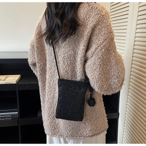 Close-up of black leopard print velvet crossbody bag with unique knot detail on side