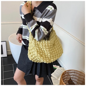 Detail shot of yellow bubble textured tote bag worn as a casual shoulder bag