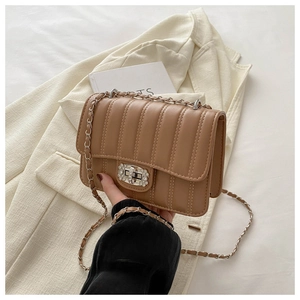 Close-up of a camel quilted bag with a round diamond twist lock and leather chain strap