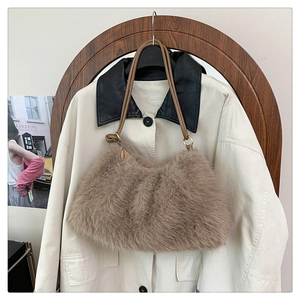 Detail view of brown plush faux fur bucket bag with leather strap on a beige coat