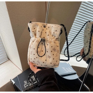Detailed close-up of cream corduroy crossbody bag with bow patterns and drawstring
