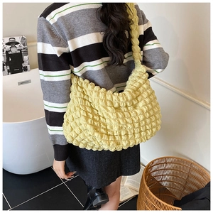 Detail of light yellow bubble textured tote bag shoulder strap and puffy fabric design