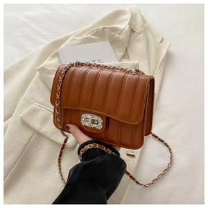 Detail of brown quilted bag with silver rhinestone turn-lock and chain strap