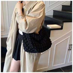 Close-up of black cloud bag with bubble texture and metallic chain detail on model