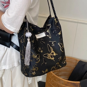 Sac seau en toile noire avec broderie papillon dorée et breloque à pompon perlé