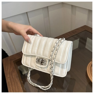 Detail of white quilted chain bag featuring a rhinestone buckle and silver metal strap
