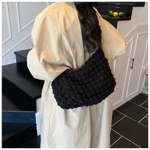 Close-up of a black textured hobo shoulder bag with quilted bubble fabric on model