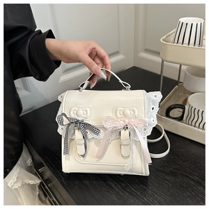Détail du sac à main blanc crème avec bordure en dentelle et motifs nœuds gaufrés