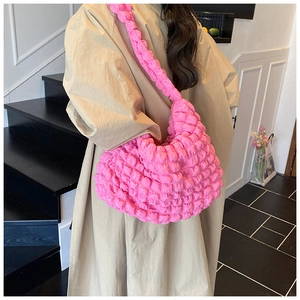 Detail of hot pink popcorn fabric texture on a crescent shoulder bag worn by model
