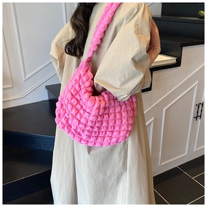 Detail of pink popcorn textured hobo bag worn by a model in a beige trench coat