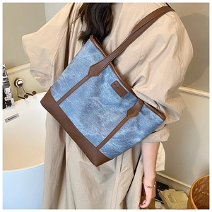 Modella che indossa una borsa tote in denim blu e pelle in un ambiente moderno