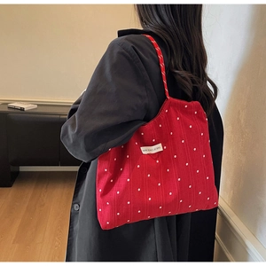 Détail d'un sac cabas en mousseline rouge avec motif floral et étiquette latérale