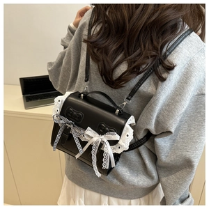 Detail view of a black PU leather backpack with lace trim and bows on a female model
