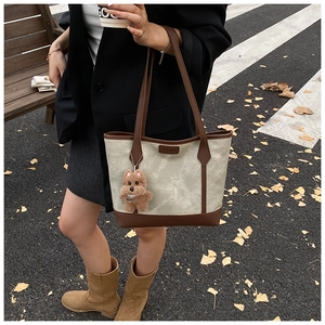 Dettaglio della borsa tote in tela con spalline in ecopelle marrone e ciondolo a cane