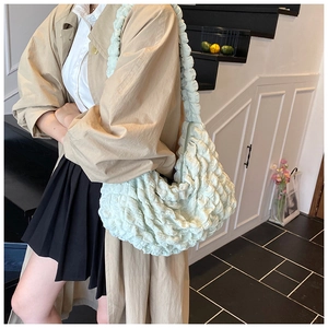 Detail of light green bubble texture shoulder bag styled with a beige trench coat