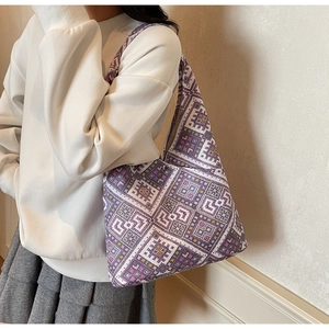 Dettaglio della borsa tote in maglia con motivi geometrici etnici viola sulla tracolla