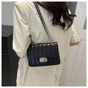 Detail of black quilted chain bag featuring silver lock with rhinestones on model