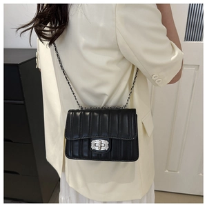 Detail of a black quilted leather shoulder bag with silver diamond turn-lock and chain strap