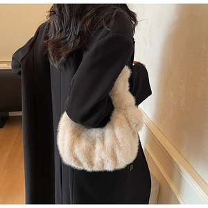 Détail de la texture d'un sac hobo en fausse fourrure crème porté par un mannequin