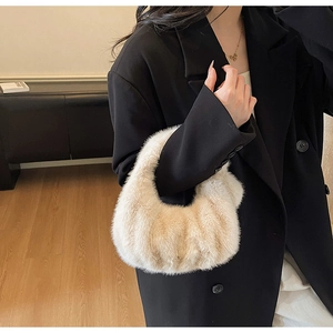 Gros plan d'un sac à main en peluche crème assorti à un blazer noir dans un décor élégant