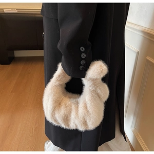 Détail d'un sac à main en peluche crème en forme de croissant avec manteau noir