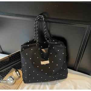 Close-up of black floral canvas tote with striped handles next to a laptop and headphones