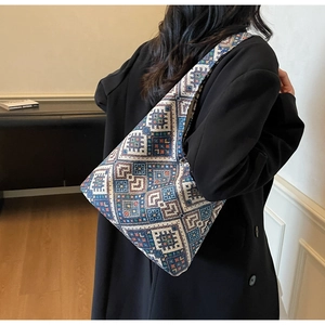 Dettaglio del motivo jacquard etnico geometrico su una borsa tote indossata sopra un cappotto