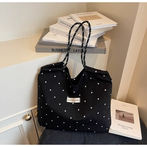 Détail du sac cabas à fleurs noires avec motifs de pétales blancs et anses en corde