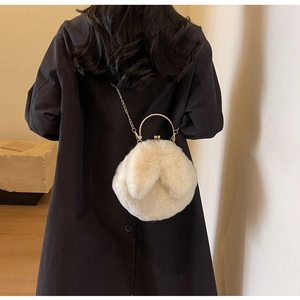 Détail du sac lapin en peluche avec poignée dorée et bandoulière sur manteau noir