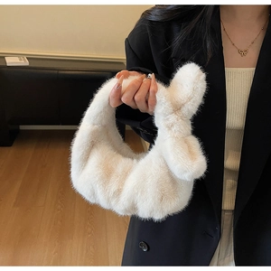 Gros plan sur un sac à main en peluche blanc crème avec fausse fourrure et nœud chic