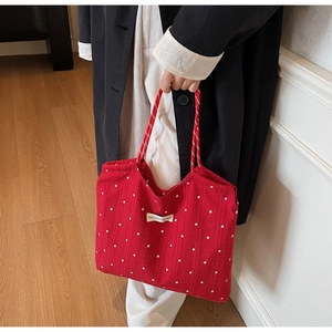 Détail du sac cabas en mousseline rouge à fleurs avec anses en corde et logo de marque