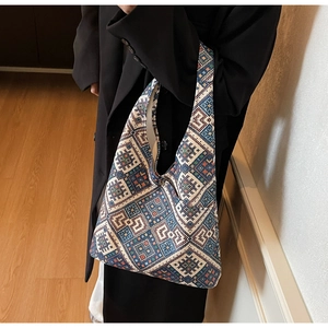 Borsa tote etnica in maglia con motivi geometrici colorati indossata su cappotto nero