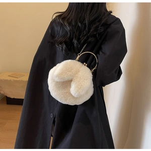 Détail d'un sac à main en peluche avec poignée ronde dorée et bandoulière chaîne