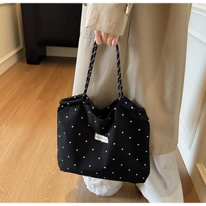 Detail of black floral tote bag with woven rope handles and white flower pattern