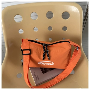 Gros plan sur un sac à bandoulière en nylon orange vif avec double fermeture éclair