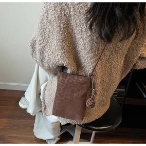 Detail view of leopard print phone bag with rope strap on a casual autumn outfit