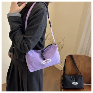 Detail von plissiertem Nylonmaterial und FANYISSA-Logo an lila und schwarzen Taschen