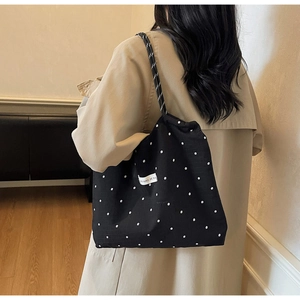 Détail du sac cabas en mousseline noire à fleurs avec anses tressées et étiquette tissu