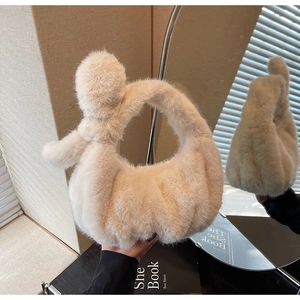 Gros plan du sac à main en peluche crème avec poignée nouée montré dans le miroir
