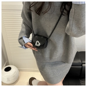 Mini black saddle crossbody bag with silver heart clasp shown on a model for scale