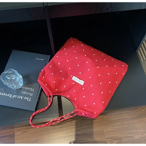 Détail d'un grand sac cabas rouge à fleurs avec étiquette et anses tressées