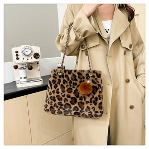 Detail of leopard print faux fur shoulder bag with gold chain strap and plush pompom charm