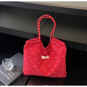 Détail du cabas en mousseline rouge à fleurs avec anses en corde et étiquette tissée