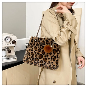 Detail of plush leopard print handbag with gold chain strap and faux fur pompom charm