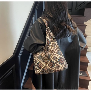 Borsa tote etnica con motivi geometrici indossata da una modella su sfondo di lusso